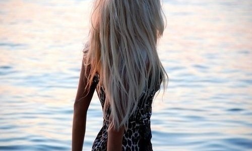 блондинка с длинными волосами спиной в платье с леопардовым принтом на море