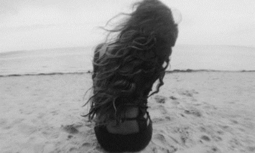волосы на ветру у девушки в платье со спины которая сидит на берегу моря