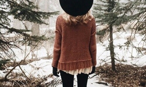 девушка в вязаном свитере спиной в зимнем лесу