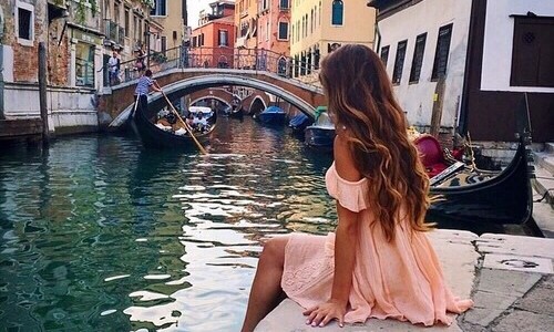 девушка в легком розовом платье со спины сидит на берегу не видно лица
