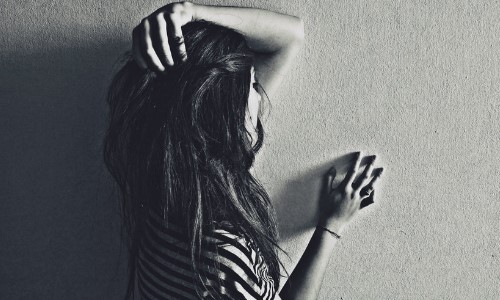 черно белое фото девушки в полосатой футболке спиной у стены